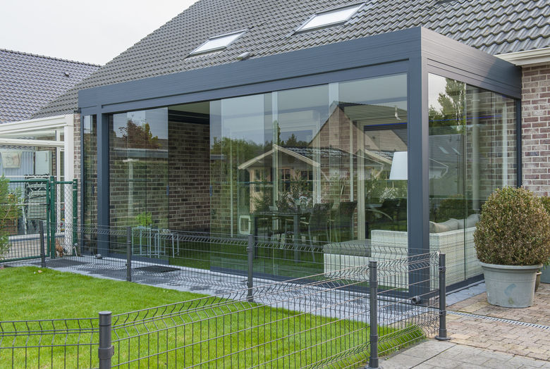 Een terrasoverkapping met lamellen dak en volledig afsluitbaar met glazen wandpanelen